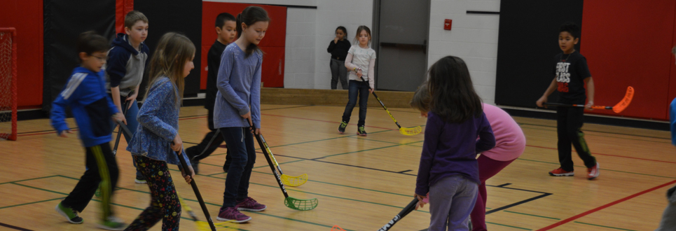 A group of students playing hockey in the school gym.