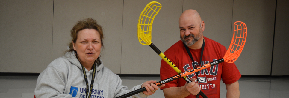 Female and Male teachers holding hockey sticks